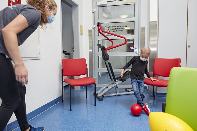 Ein Krebskranker kleiner Junge, der auf der Station mit einer Sporttherapeuthin Ball spielt
