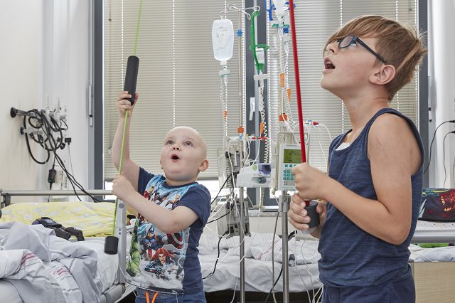 Zwei krebskranke Kinder, die im Patientenzimmer an einem Seilzug spielen