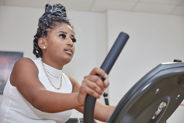 Eine krebserkrankte junge Frau auf dem Crosstrainer