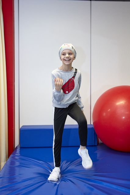 Ein krebskrankes Mädchen, das auf einer Sportmathe schonende Übungen ausführt